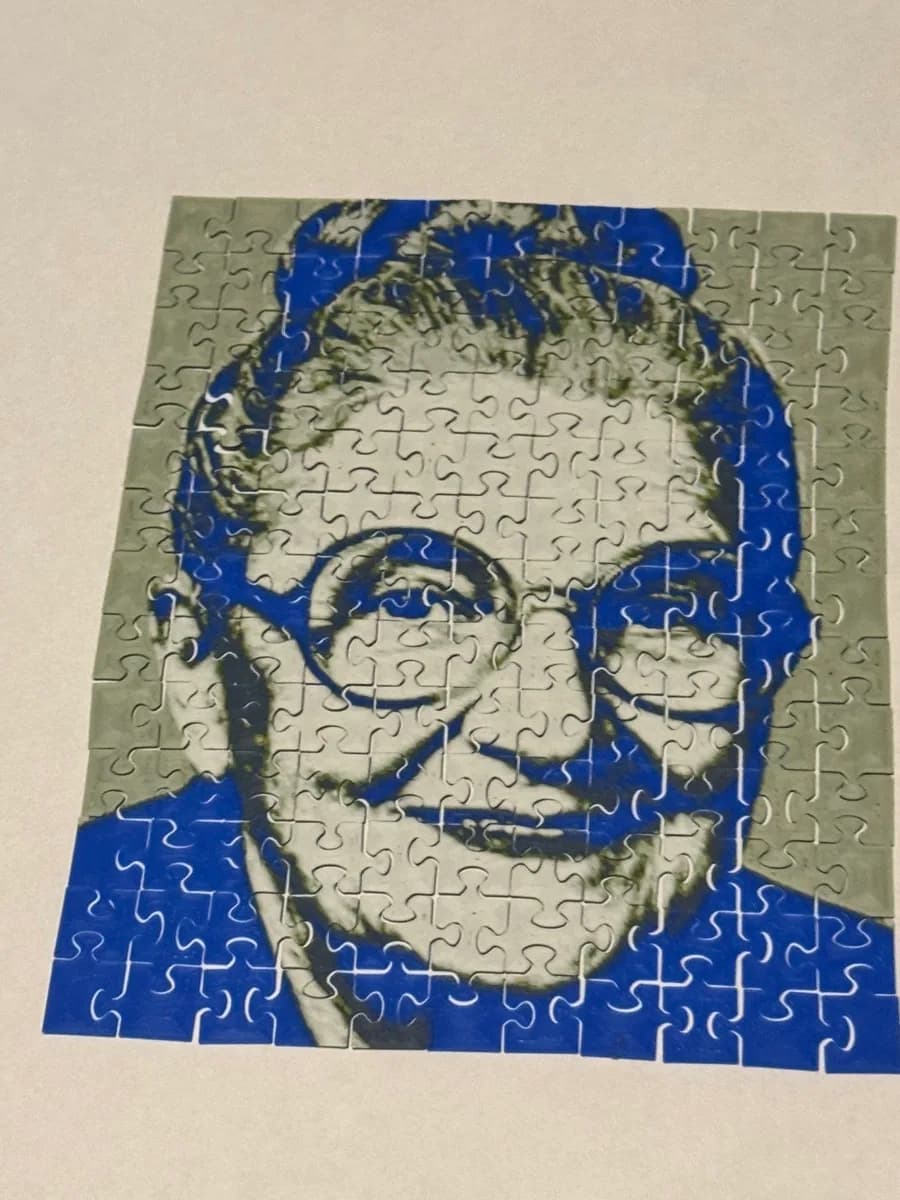 A blue and white 3D printed photo puzzle of a grandmother, assembled on a white table