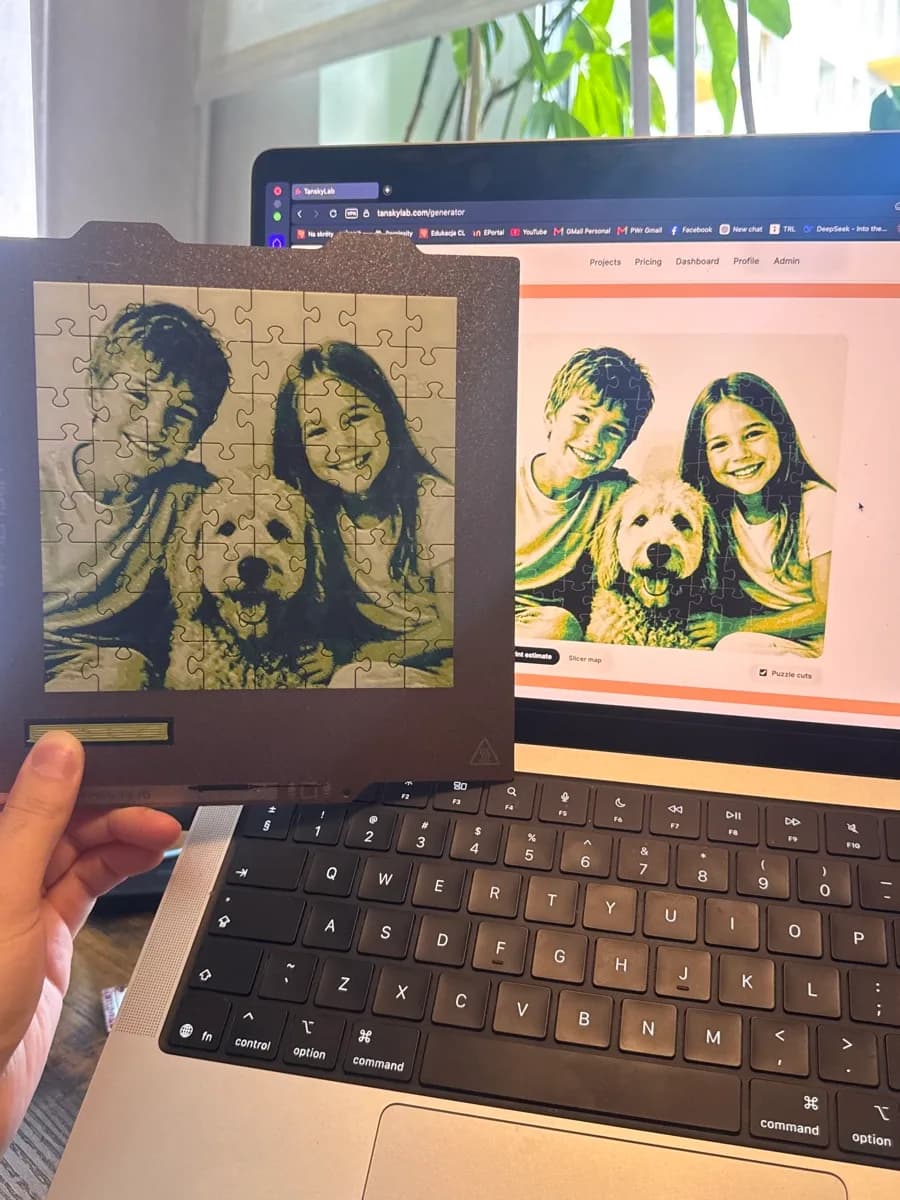 A freshly printed photo puzzle of two children and a dog held in front of a laptop showing the original photo